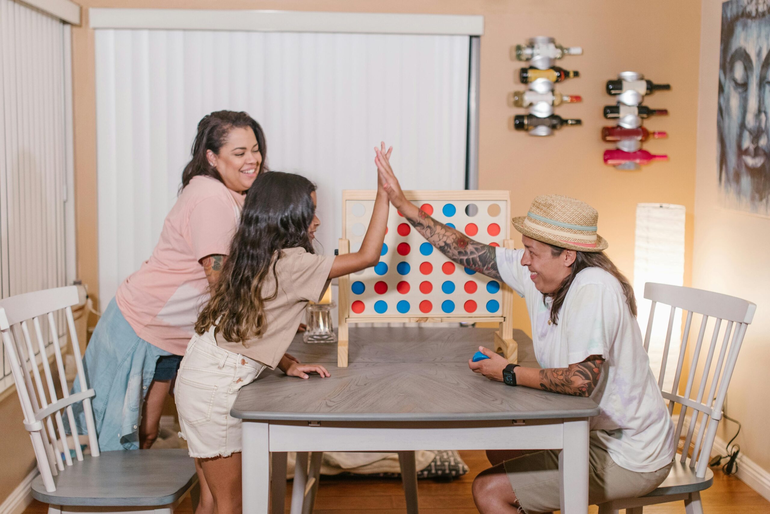 Happy family playing a board game and high-fiving in a cozy indoor setting.